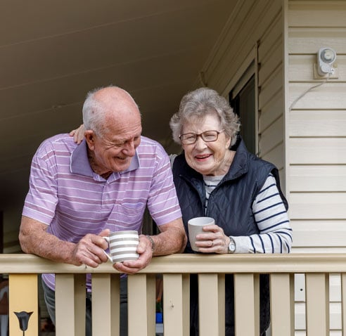 Elder couple on their porch holding mugs